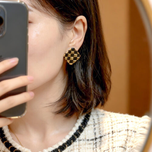 black and gold checkerboard stud earrings worn by model